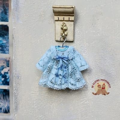 Miniatuur babyjurkje blauw 1:12 – handgemaakt poppenhuis kledingstuk